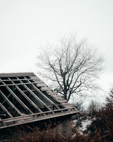 Image of a UK house roof with visible sagging and missing tiles under cloudy sky.