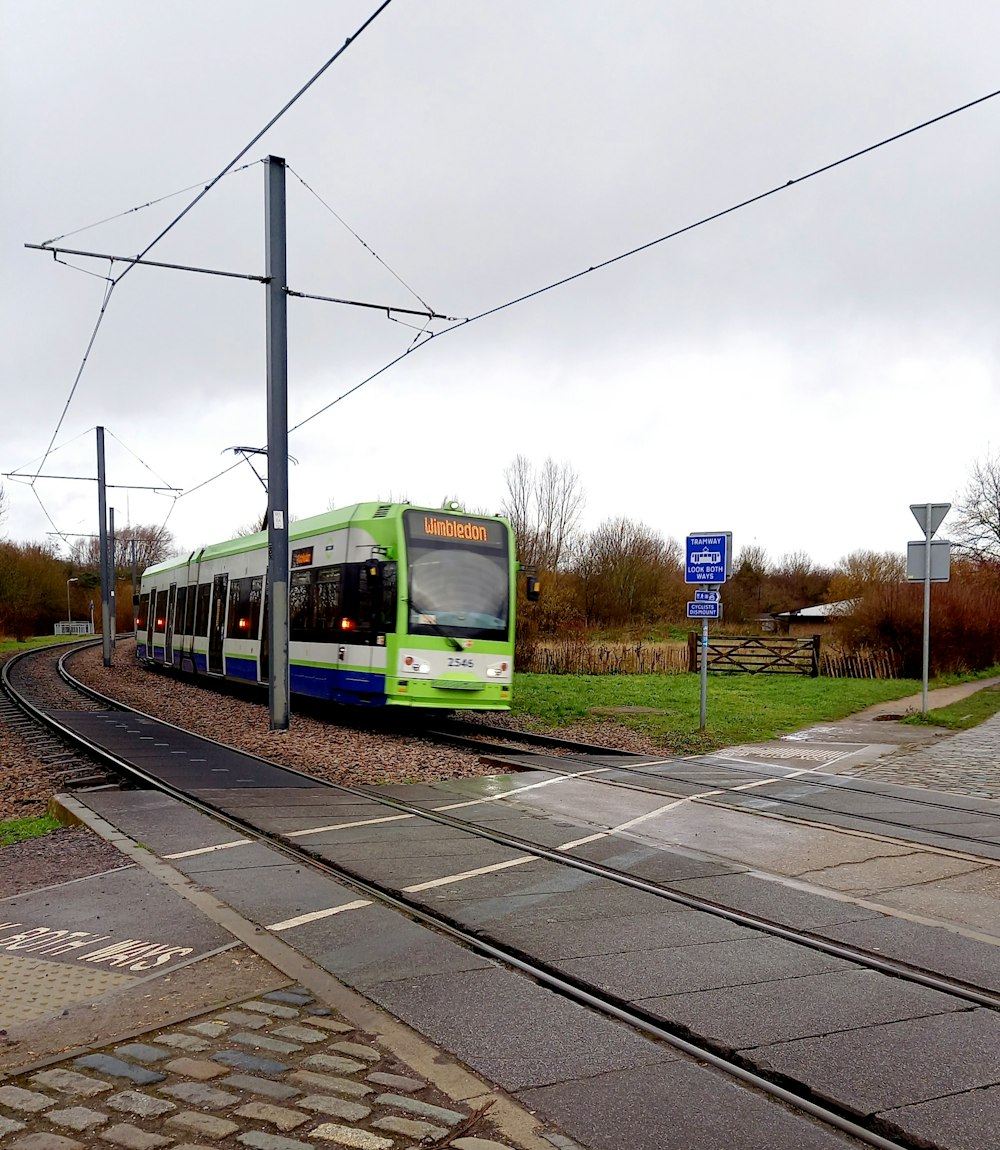 green and yellow train on rail tracks under blue sky during daytime