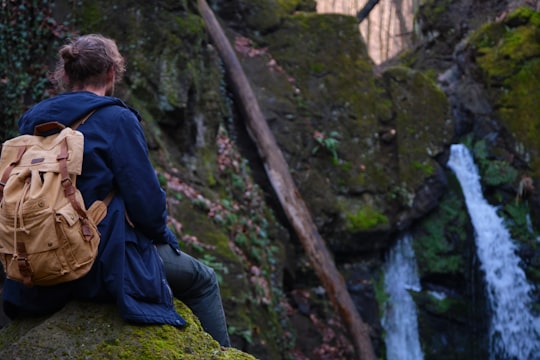 man in blue jacket and black pants sitting on rock in Parád Hungary