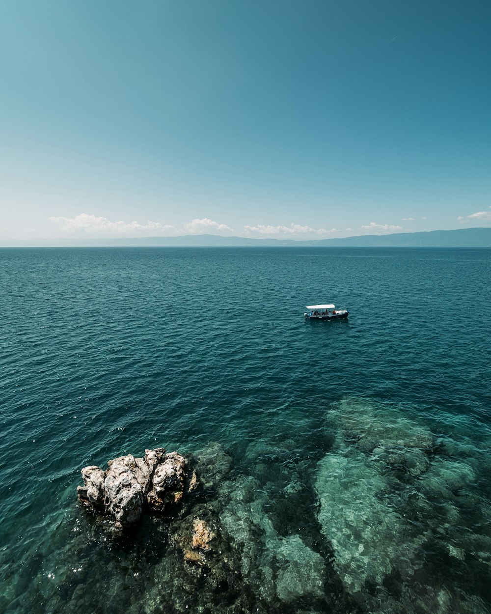 white boat on sea under blue sky during daytime