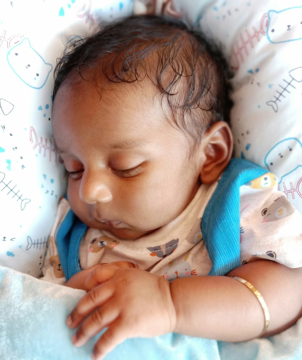 baby in blue and white stripe shirt lying on white textile