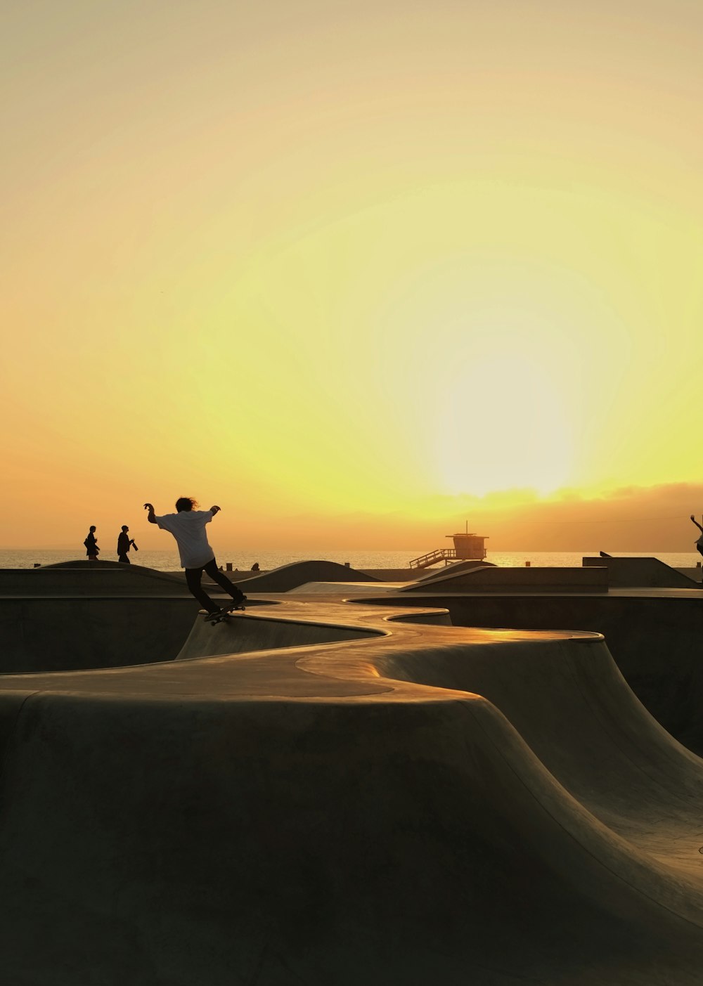 Silueta del hombre montando patineta durante la puesta del sol