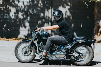 A motorcycle instructor helping a student with riding techniques on a sunny day.