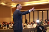 man in black suit standing on stage