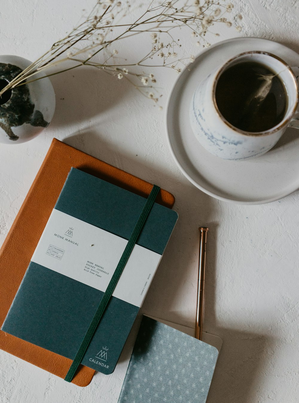 white ceramic mug with coffee beside green book