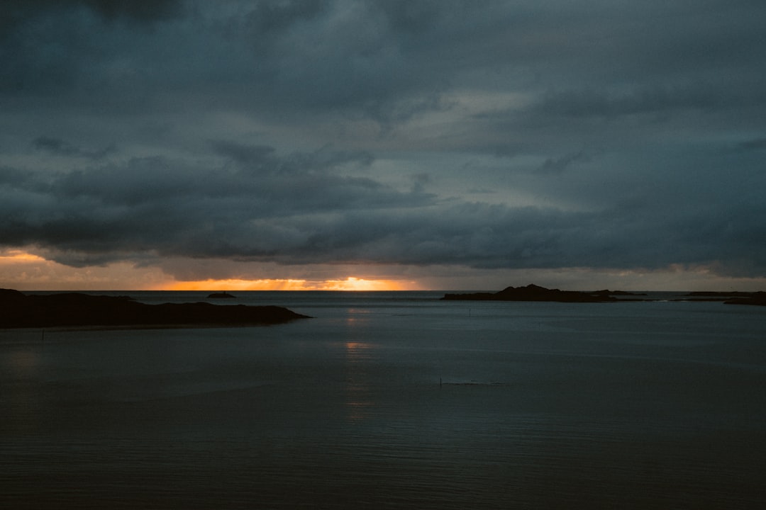 body of water under cloudy sky during sunset