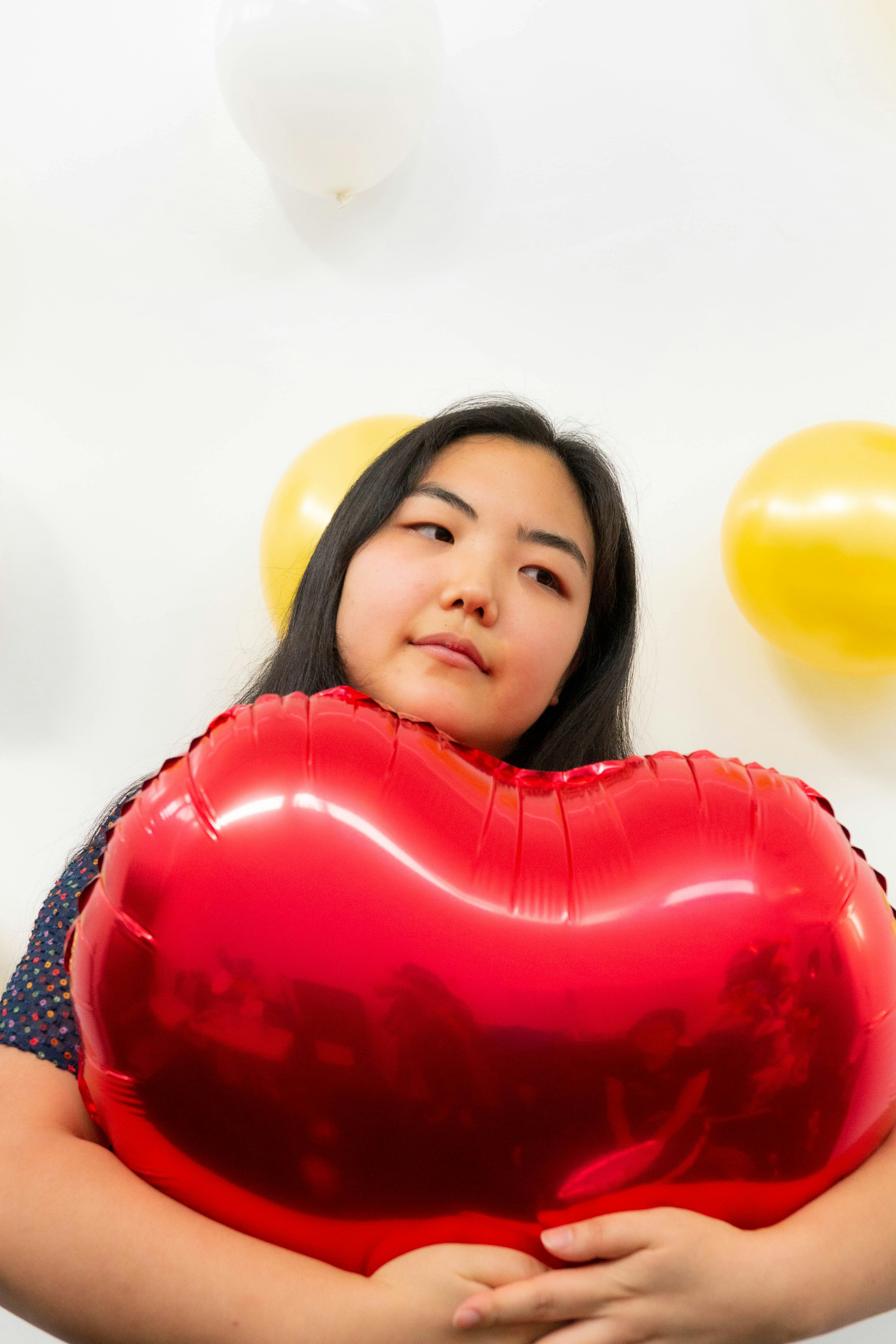 girl in red and white shirt holding heart balloon