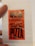 A red sticker with a jagged design borders, featuring bold black text that reads 'GROSSO NAPOLETANO SECURITY STICKER! ENJOY YOUR PIZZA'. The sticker is placed on a white piece of paper, possibly part of a receipt. A person's hand is partially visible holding the paper.