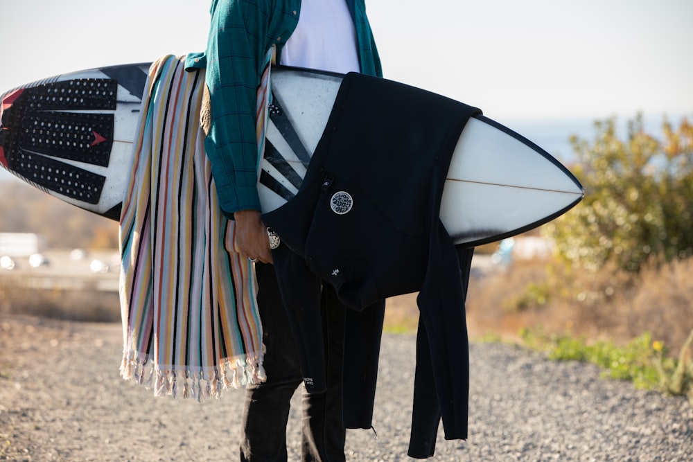 person in black pants holding black and white surfboard