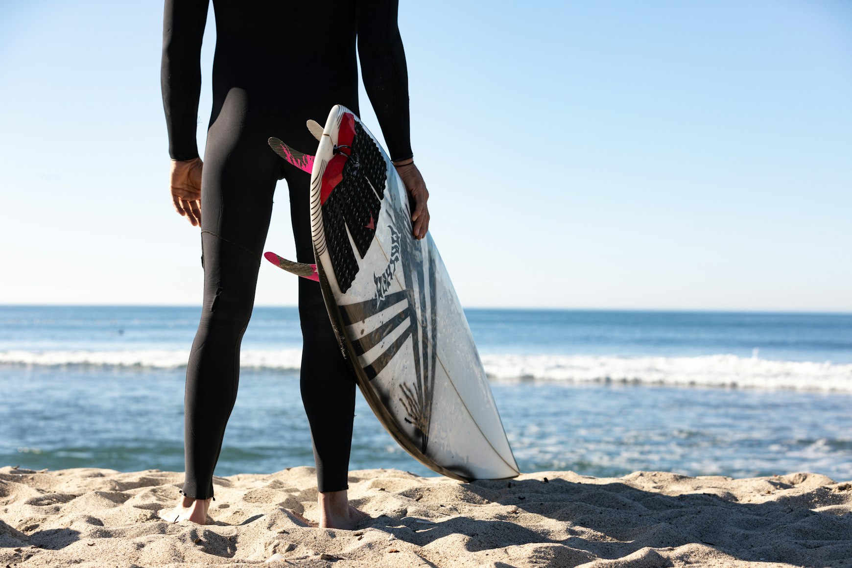 Person holding white and blue surfboard on beach