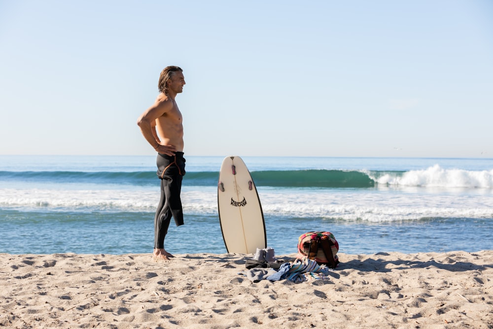 woman in blue denim shorts holding white surfboard on beach during daytime