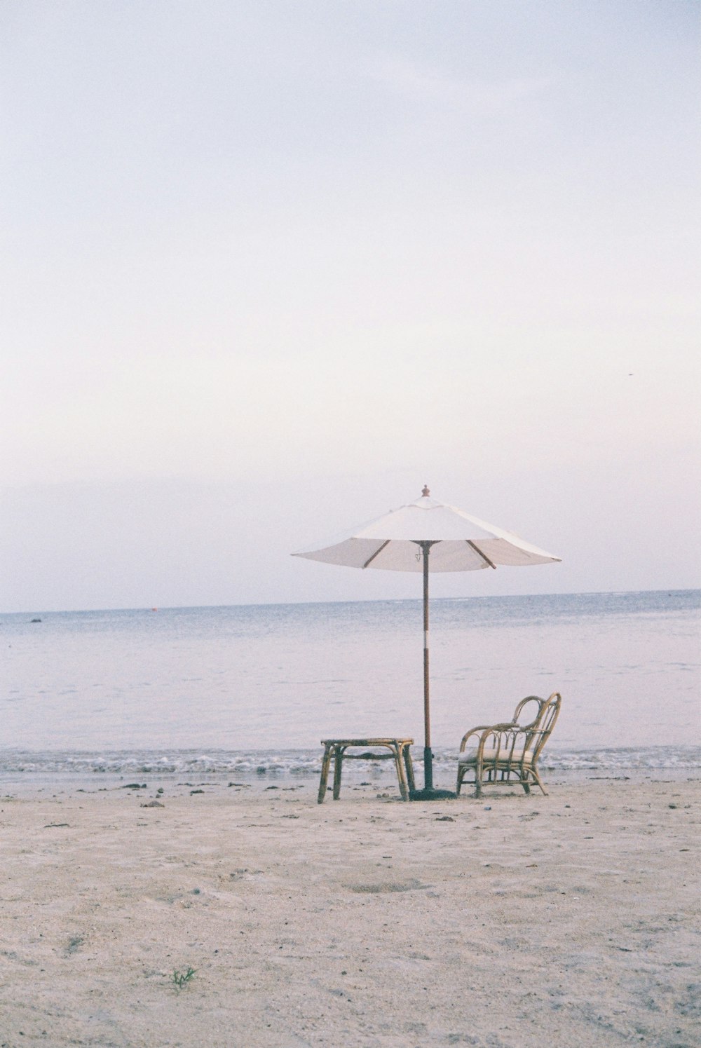 green and black wooden chair under white umbrella on beach during daytime