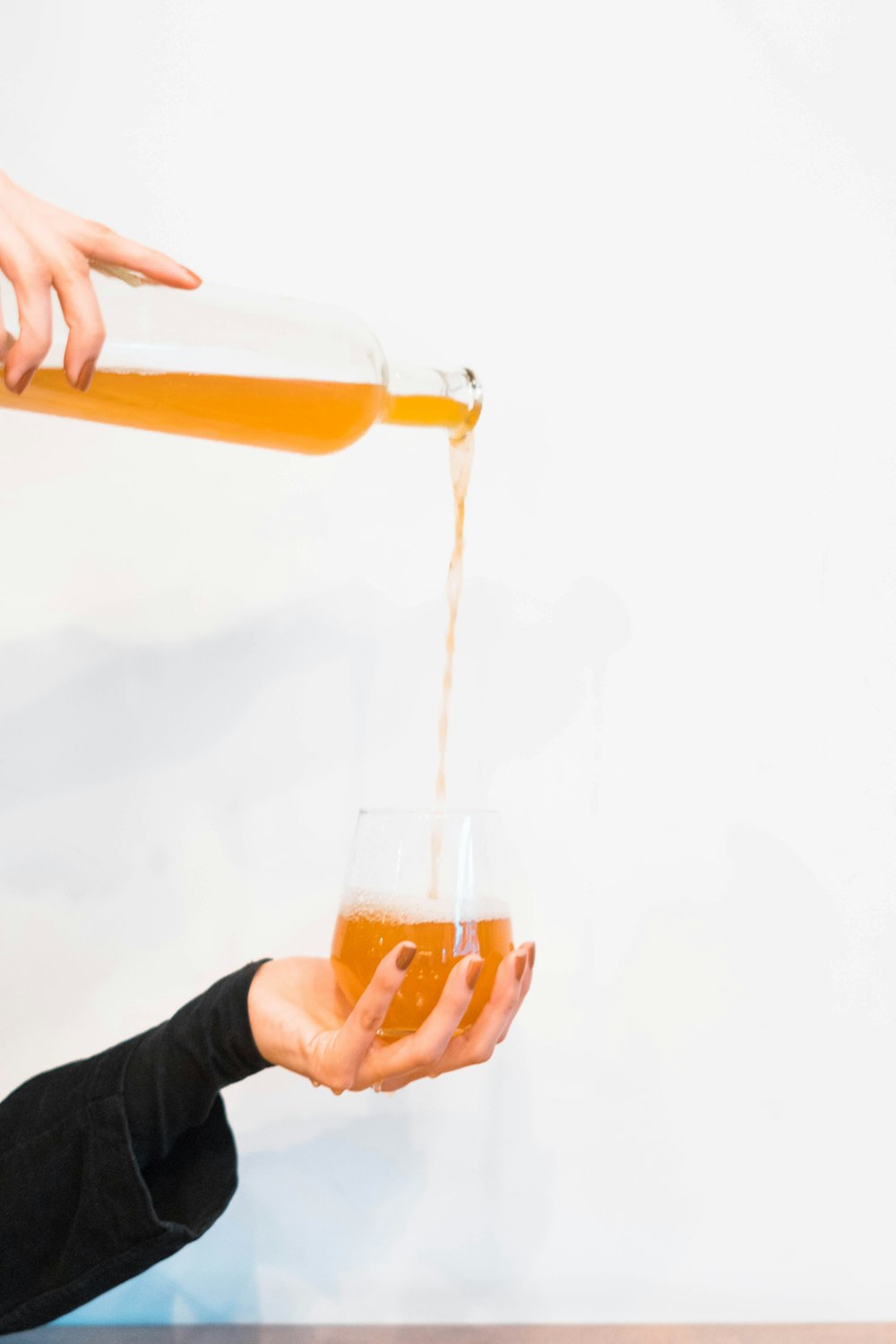 person holding clear drinking glass with orange liquid