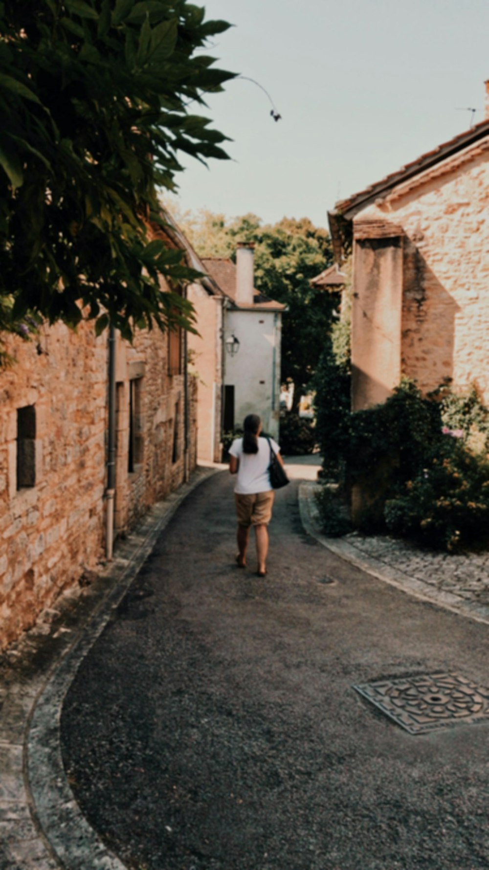 woman in white shirt and black shorts walking on street during daytime