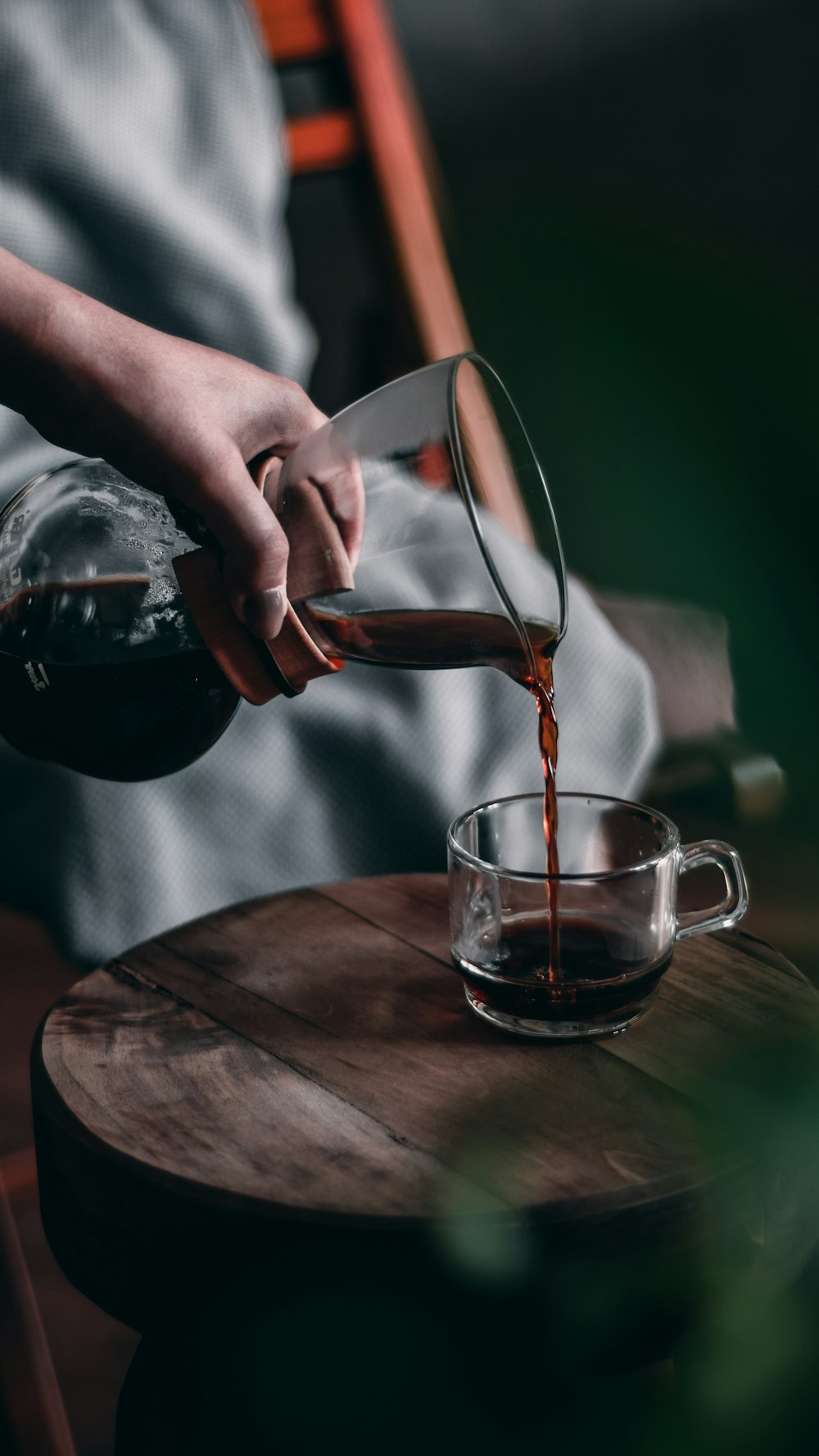 person pouring red liquid on clear glass mug