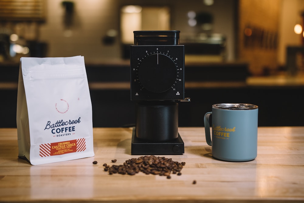 black coffee maker beside white and blue ceramic mug