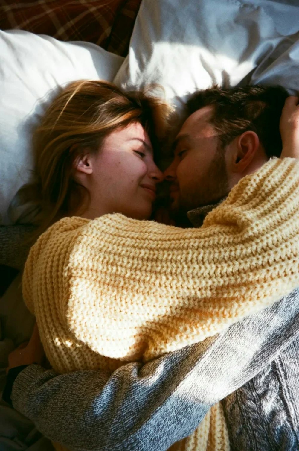 a man and woman laying in bed under a blanket