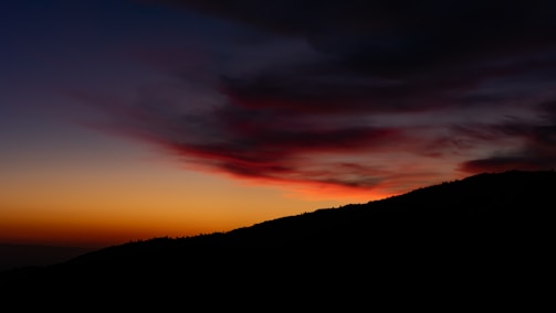 A vibrant photo of a sunset over a mountain range, highlighting rich colors.
