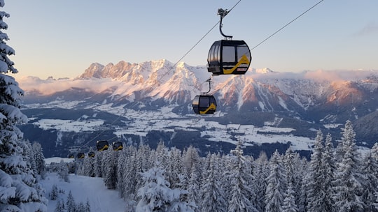 black cable car over snow covered mountain during daytime in Schladming Austria