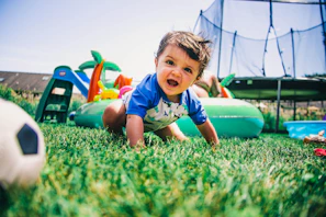 A joyful toddler crawling through a colorful sensory play area filled with vibrant toys.