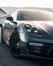 A sleek black and gold luxury car parked outside a modern Montana home at dusk.