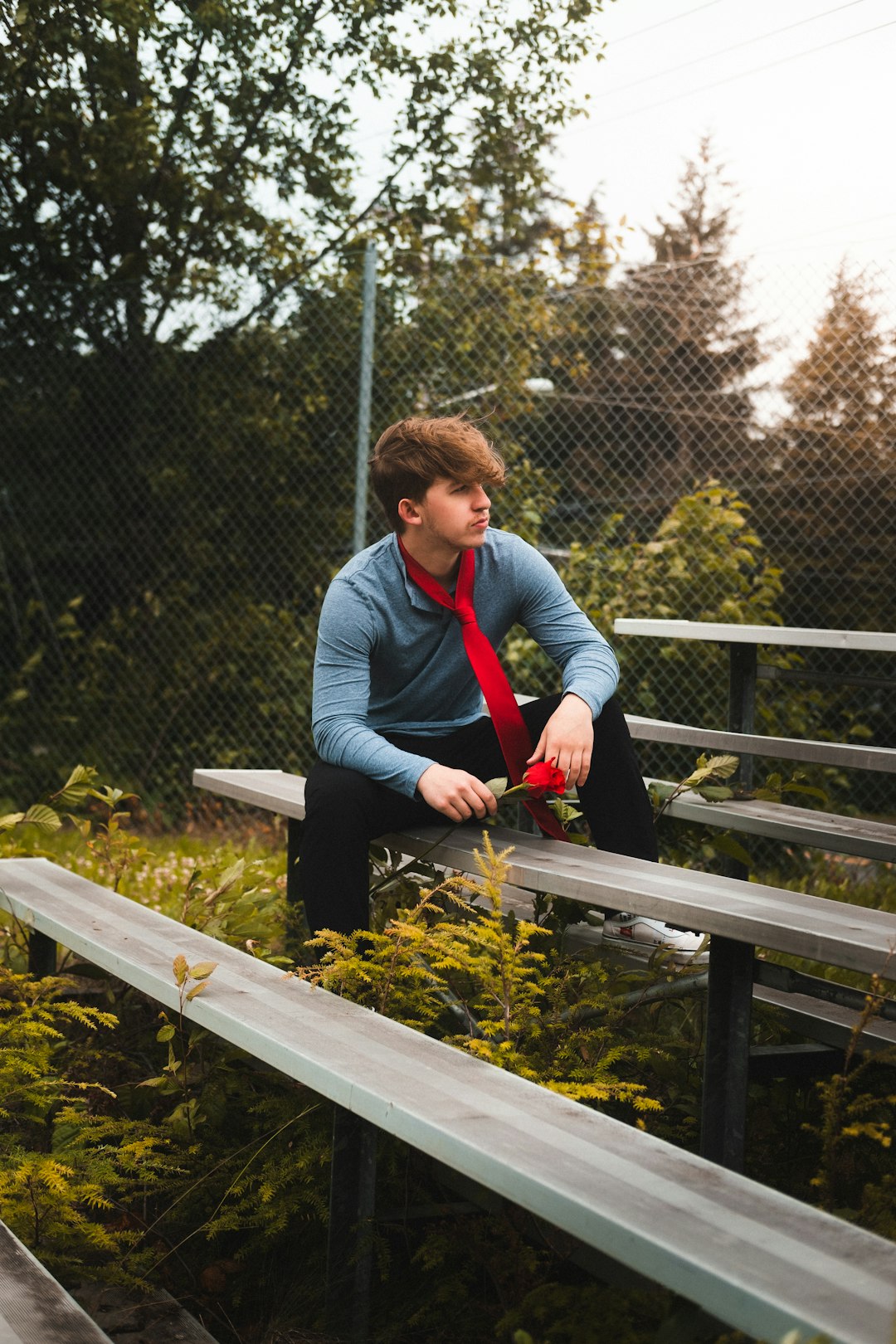 woman in gray long sleeve shirt and blue denim jeans sitting on brown wooden bench during