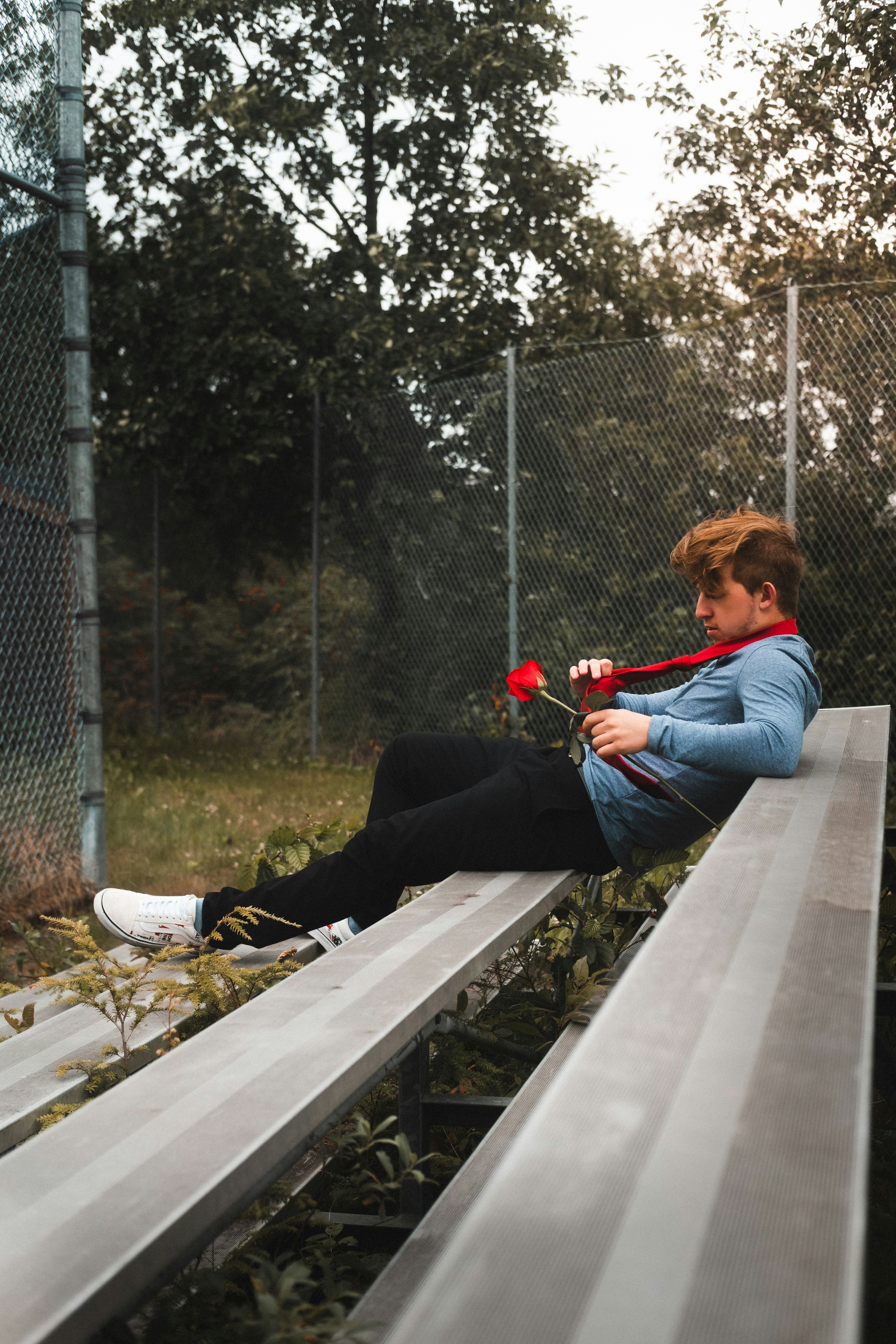 woman in blue long sleeve shirt and black pants sitting on gray wooden bench