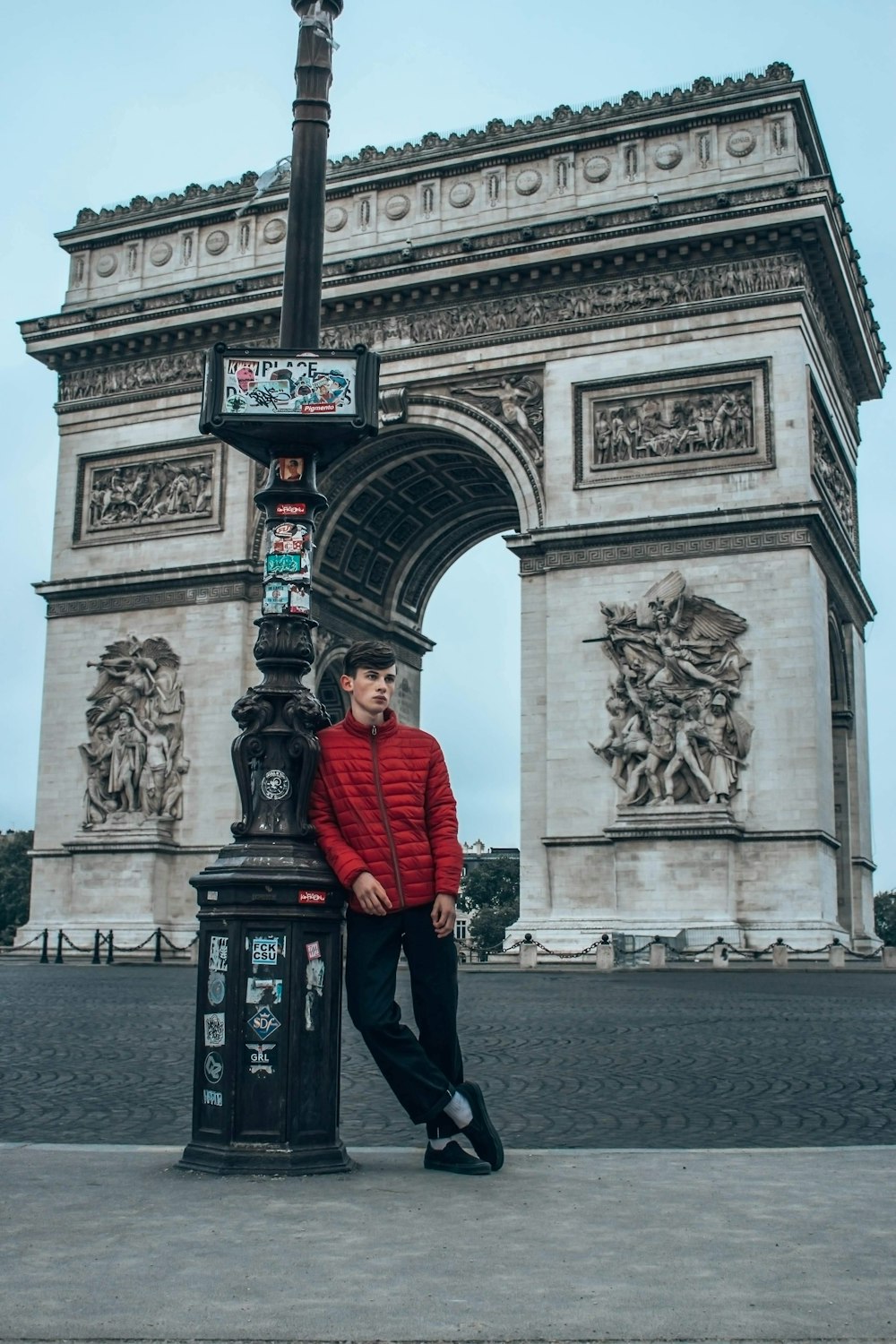 man in red jacket standing near arc de triomphe