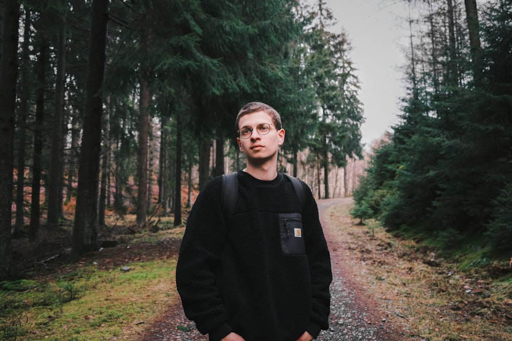 man in black jacket standing on forest during daytime