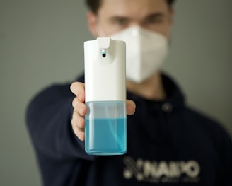 man in black hoodie holding white and blue plastic bottle