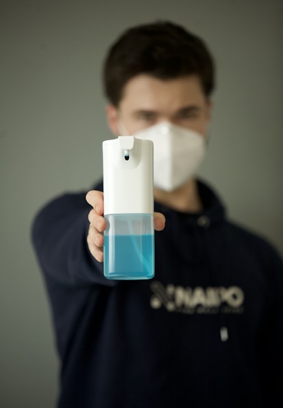 man in black hoodie holding white and blue plastic bottle