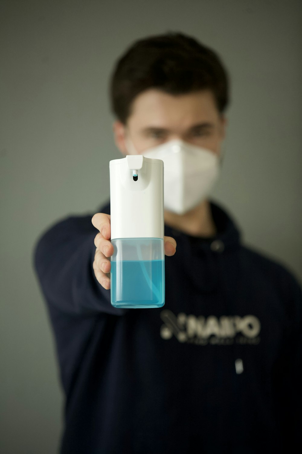 man in black hoodie holding white and blue plastic bottle