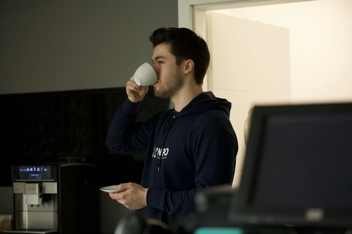 Fit man in a workout shirt holding a mug of black coffee, a common morning ritual during intermittent fasting for testosterone and fat loss.