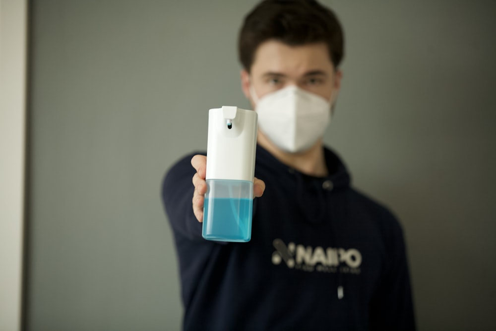 man in black and white crew neck shirt holding white and blue plastic bottle