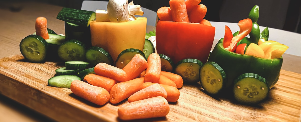 sliced carrots and green bell pepper on brown wooden chopping board