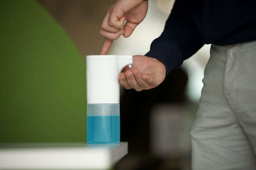 person in black long sleeve shirt holding white and blue plastic cup