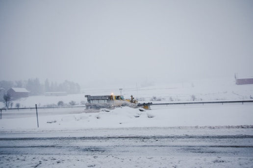 A snow-covered driveway being cleared by a snow plow.