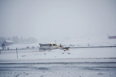 Snow clearing in progress with a large plow pushing through fresh snow on a rural road.