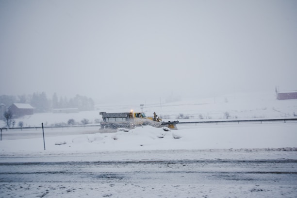 A snowplow clearing a residential driveway in Coquitlam on a snowy morning.