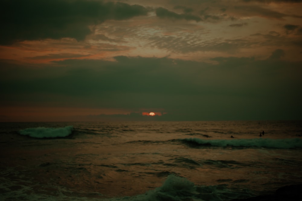 ocean waves crashing on shore during sunset