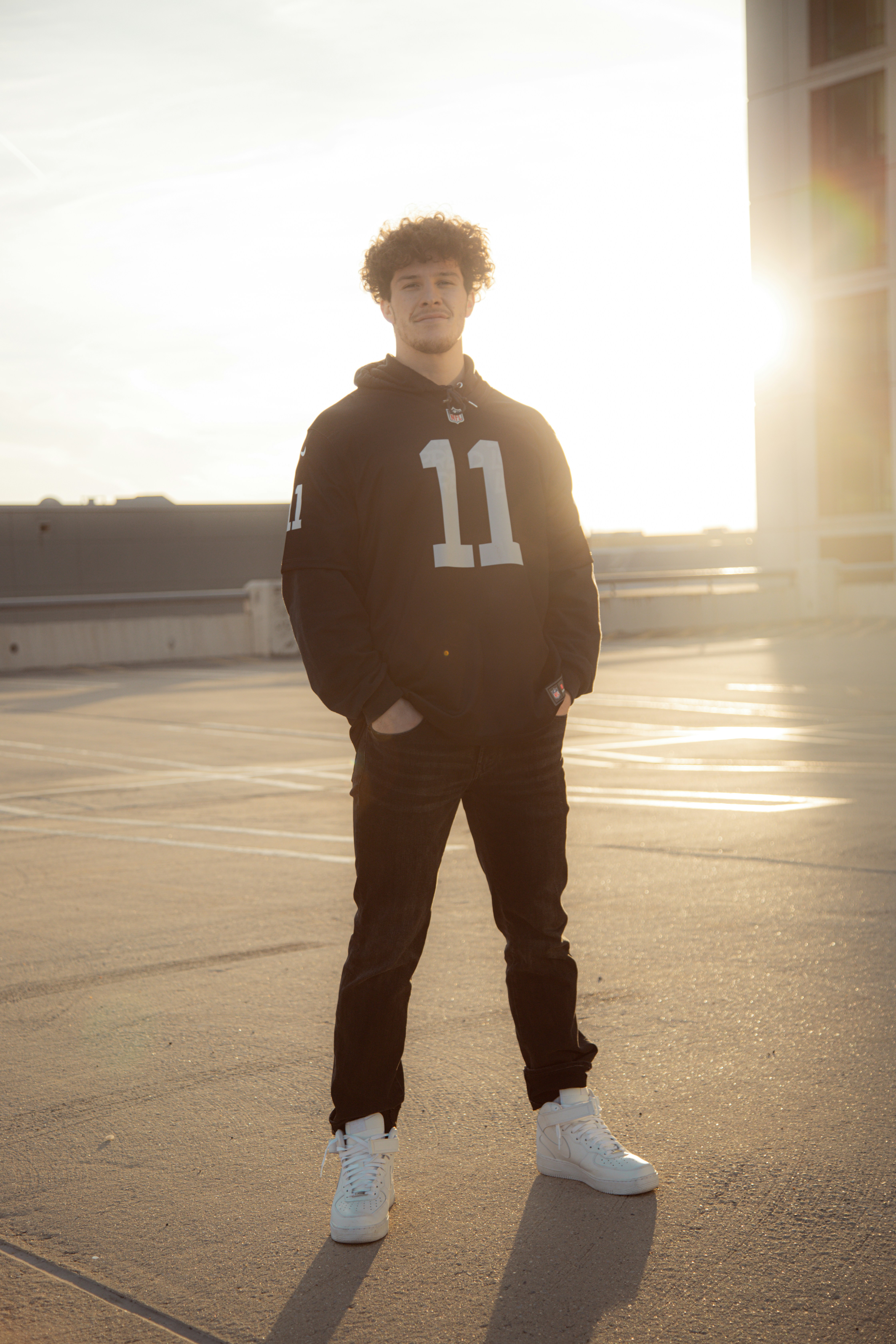 homem em jaqueta adidas preta e branca em pé na estrada durante o dia