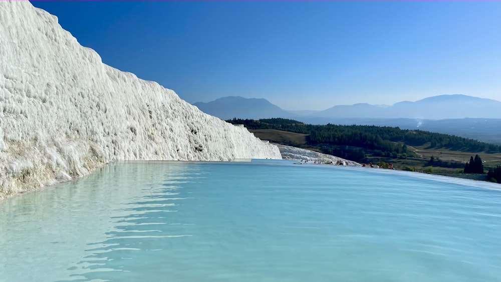 white and green mountain beside body of water during daytime