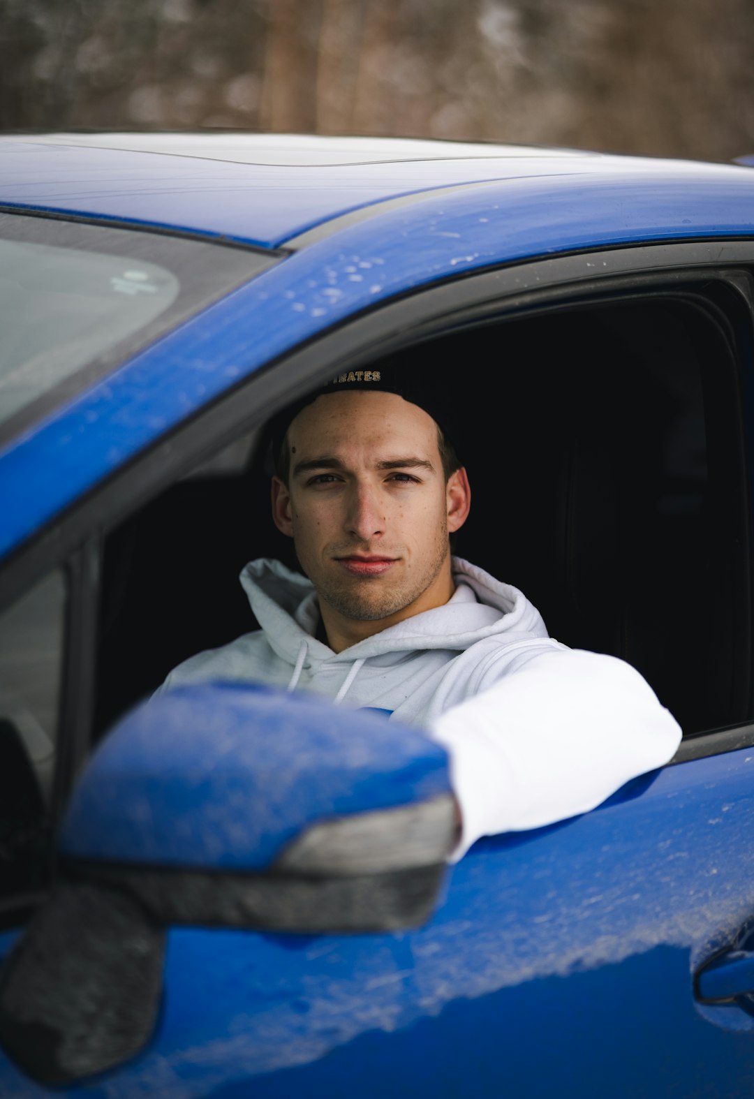 man in white and blue hoodie sitting inside car
