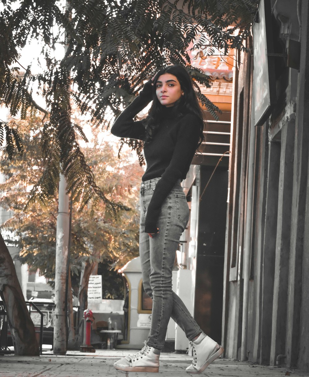 Woman in black hoodie and gray denim jeans standing beside brown wooden  wall during daytime photo – Free Brown Image on Unsplash