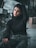 woman in black turtleneck sweater and blue denim jeans sitting on black metal fence