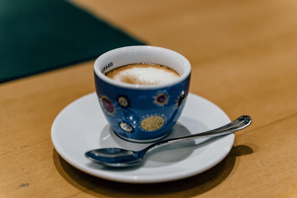 white and blue ceramic mug with coffee on white ceramic saucer