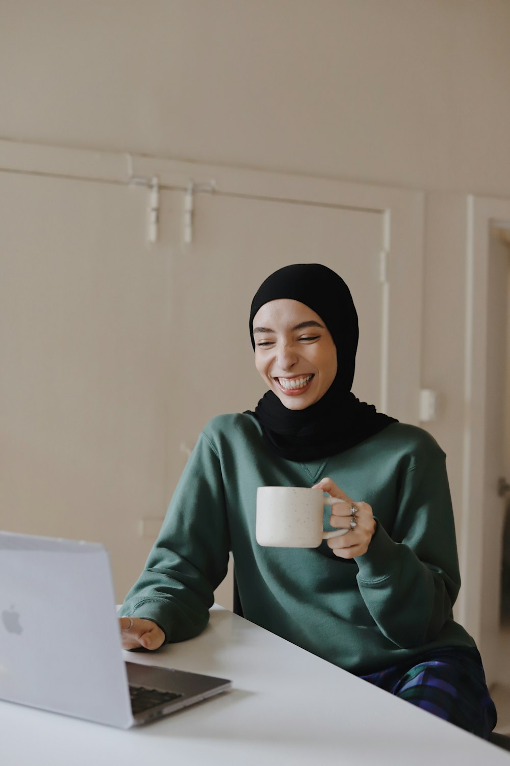 woman in green hijab holding white ceramic mug