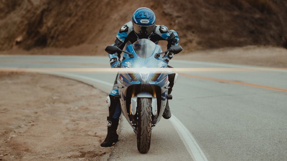 homme en costume de moto bleu et blanc conduisant une moto sur la route pendant la journée