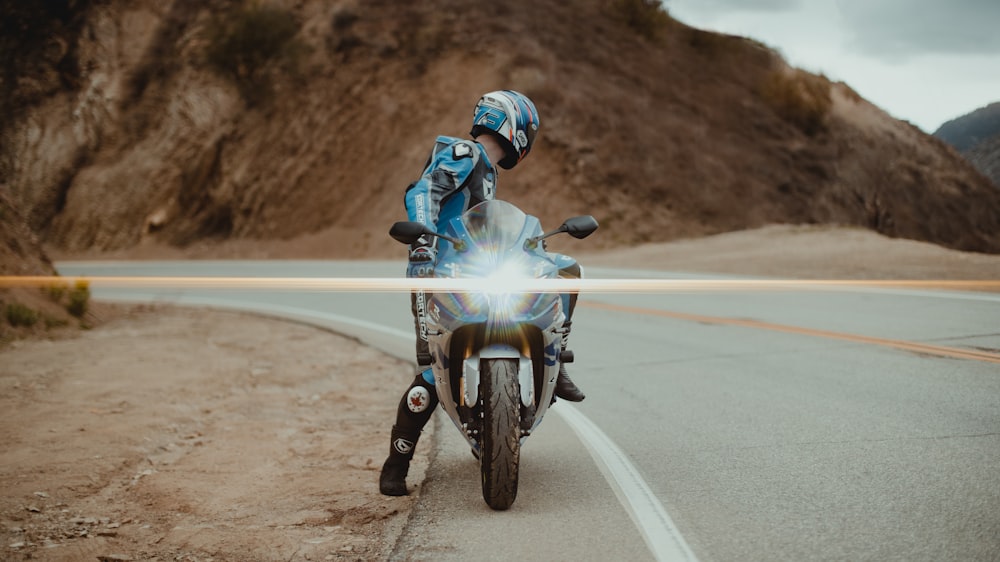 man in blue and white motorcycle suit riding motorcycle on road during daytime