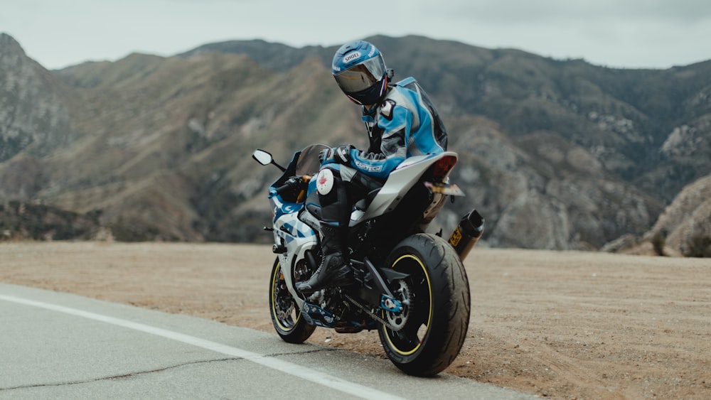 man in blue and white jacket riding black motorcycle on road during daytime